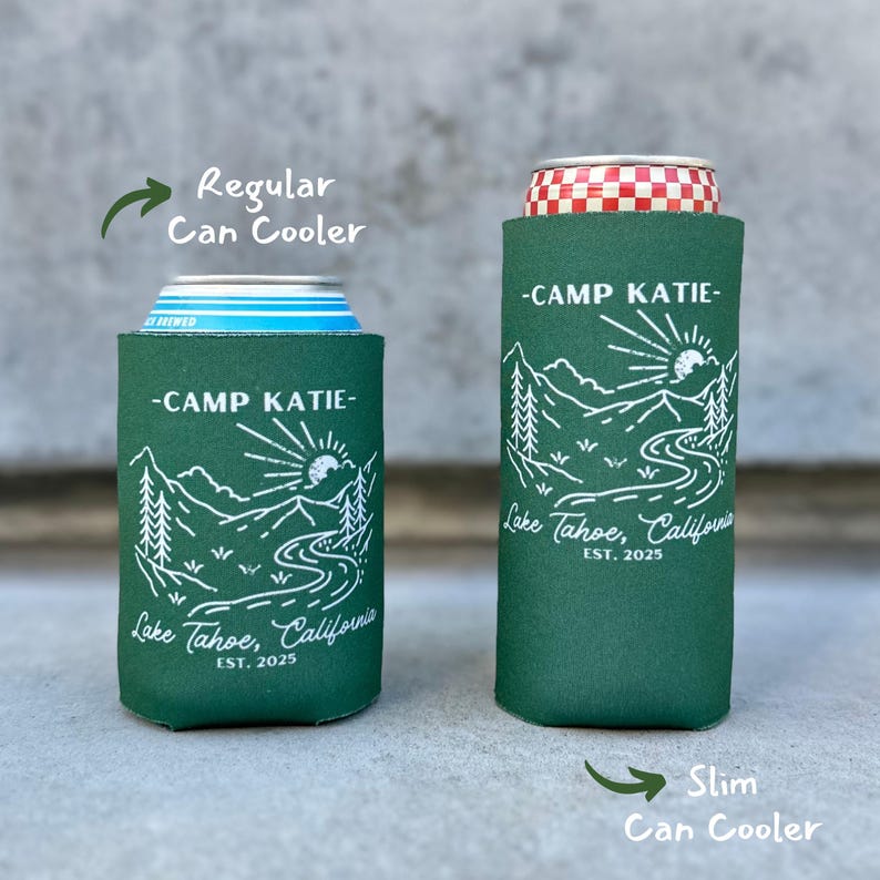 May include: Two green can coolers with a white mountain scene and the text "Camp Katie - Lake Tahoe, California - Est. 2025". The can cooler on the left is a regular size and the can cooler on the right is a slim size.