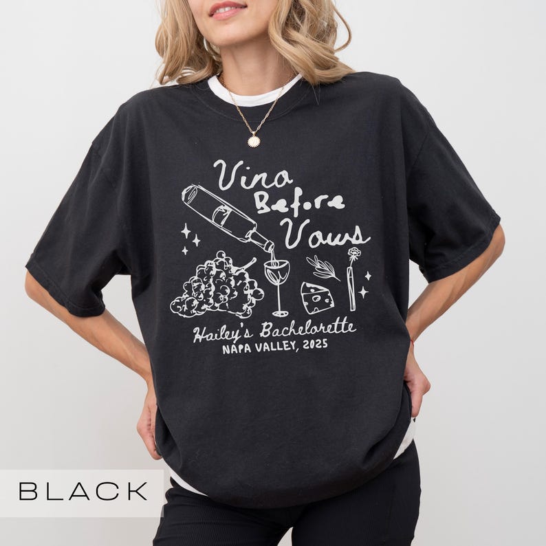 以下が含まれることがあります： 白のテキストとグラフィックが特徴の黒いTシャツ。デザインには、グラスに注がれるワインボトル、ブドウ、チーズ、「Vina Before Vows」と「Hailey's Bachelorette Napa Valley, 2025」の文字が含まれています。