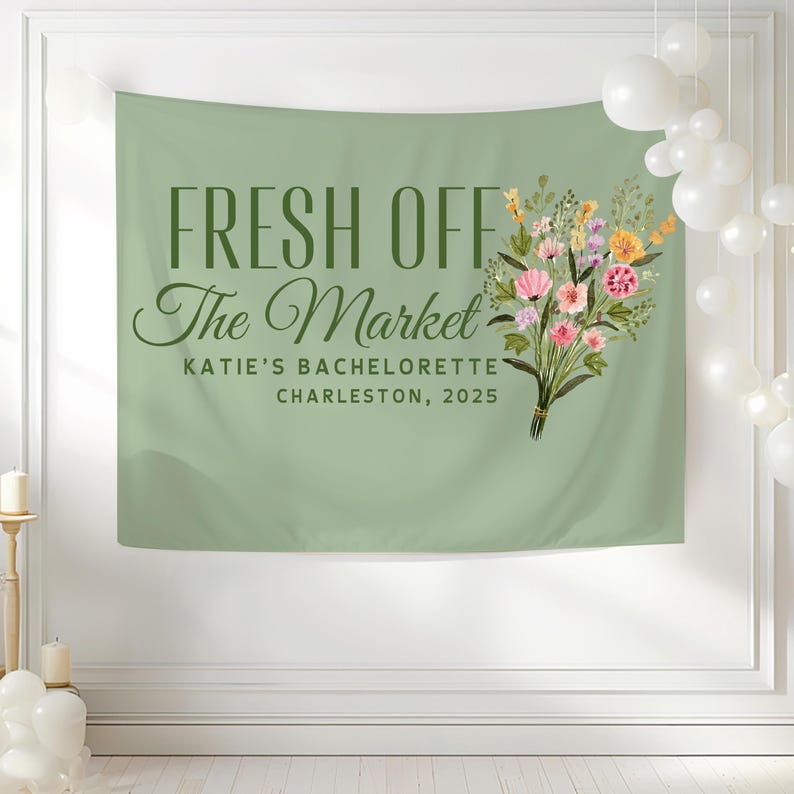 May include: A green banner with the text "FRESH OFF The Market" in green lettering. Below the text is "KATIE'S BACHELORETTE CHARLESTON, 2025" in smaller green lettering. A bouquet of pink, yellow, and white flowers is on the right side of the banner.