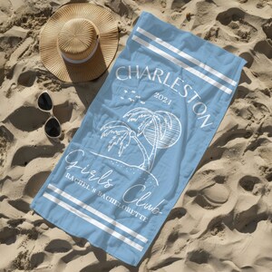 Puede incluir: Una toalla de playa azul claro con rayas blancas y el texto "Charleston 2021 Girls Club Rachel's Bachelorette" impreso en ella. La toalla presenta un contorno blanco de palmeras y un sol.