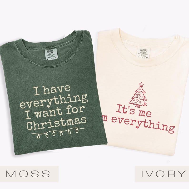 May include: Two t-shirts, one moss green and one ivory, with Christmas-themed text. The moss green shirt says "I have everything I want for Christmas" and the ivory shirt says "It's me everything" with a Christmas tree graphic.