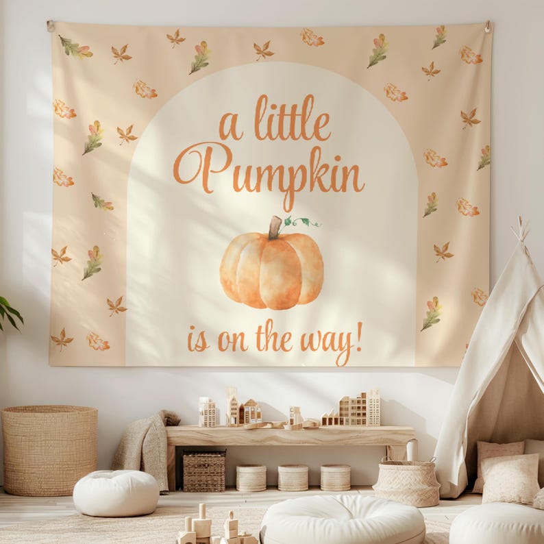 May include: A beige tapestry with a watercolor pumpkin and the text "a little pumpkin is on the way!" surrounded by small orange and brown leaves.