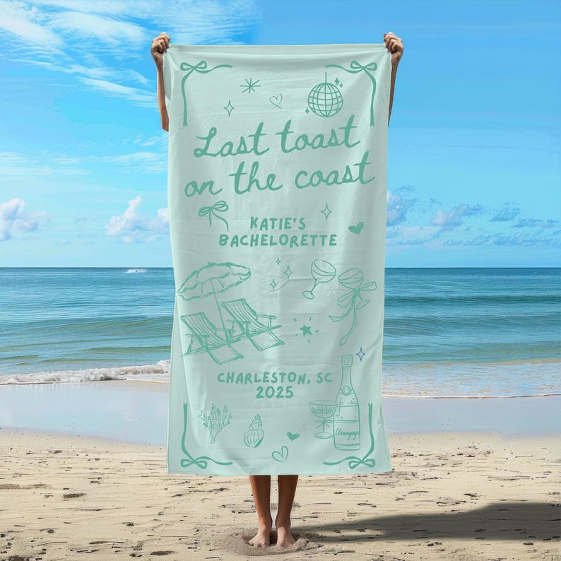 May include: A light blue beach towel with the text "Last toast on the coast" and "Katie's Bachelorette" in a green font. The towel also features a beach scene with palm trees, beach chairs, and a cocktail glass. The text "Charleston, SC 2025" is printed at the bottom of the towel.