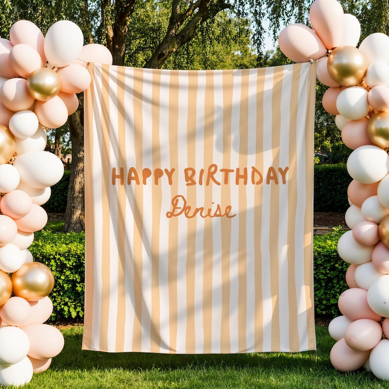 Puede incluir: Un tel&oacute;n de fondo a rayas crema y naranja con el texto "HAPPY BIRTHDAY Denise". Globos blancos, dorados y melocot&oacute;n enmarcan el tel&oacute;n de fondo, creando un ambiente festivo. Ideal para una fiesta de cumplea&ntilde;os.