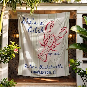 May include: A white and green striped banner with the text "She's a Catch" in blue script. A red lobster illustration is centered, with "EST. 2025" below. The banner reads "Katie's Bachelorette, Charleston, SC."