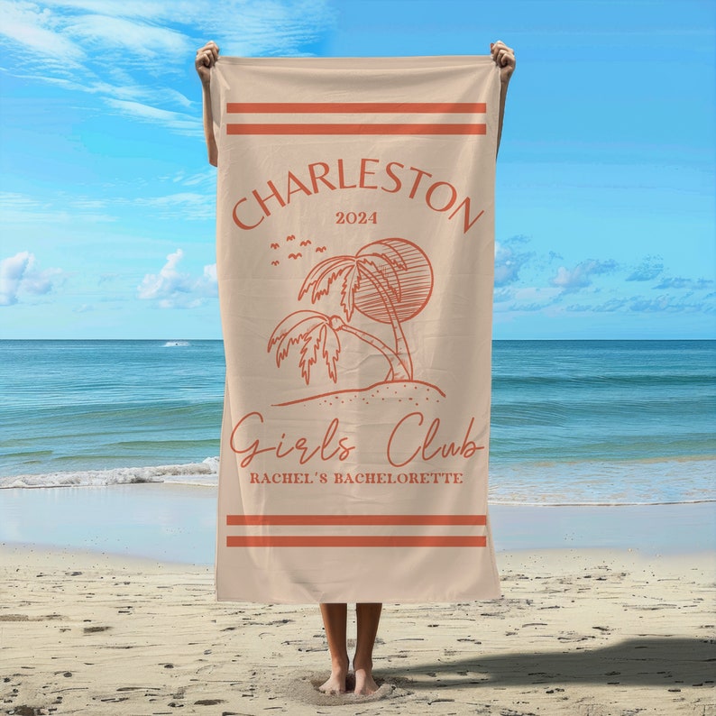 Puede incluir: Una toalla de playa de color beige con un borde de rayas rojas y blancas. La toalla presenta un dise&ntilde;o de palmera con un sol y el texto "Charleston 2024 Girls Club Rachel's Bachelorette" en rojo.