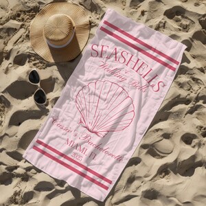 May include: Pink beach towel with the text "Seashells & Wedding Bells" and a red seashell illustration. The text "Cassie's Bachelorette Miami, FL 2025" is also printed on the towel.