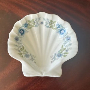 May include: A white ceramic seashell-shaped dish with a blue and green floral design.