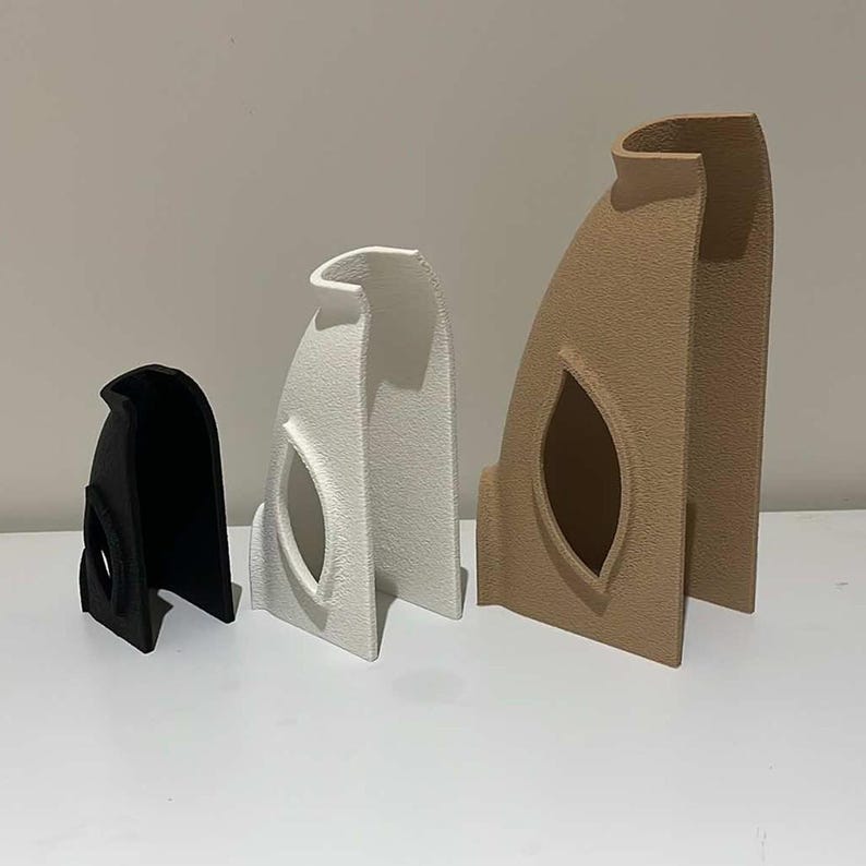 Peut inclure: Trois vases en c&eacute;ramique de diff&eacute;rentes tailles, noir, blanc et marron. Chaque vase a un design unique avec une d&eacute;coupe en forme de feuille.