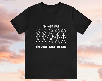 May include: Black t-shirt with a white graphic of stick figures. The text on the shirt reads "I'm not fat, I'm just easy to see."