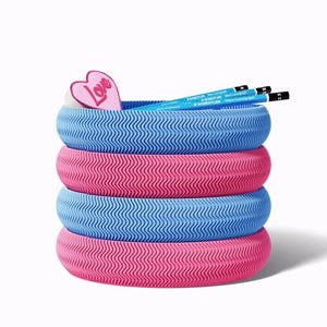 May include: A stack of four colourful, textured pencil holders in pink and blue. A pink heart-shaped decoration with the word "Love" is on top, along with two pencils. The holders have a wavy pattern.