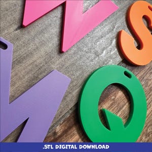 May include: A set of colorful 3D printed letters, including a pink "Z", a purple "N", an orange "S", and a green "Q". The letters are arranged on a wooden surface.  .STL Digital Download