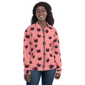 May include: A pink bomber jacket with a black cat face pattern. The cat faces are wearing red bandanas.