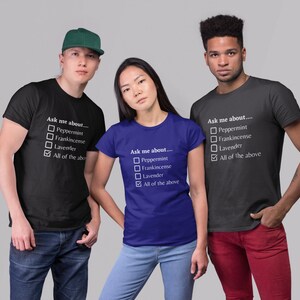 May include: Three people wearing black and blue t-shirts with the text "Ask me about..." and a checklist of options. The options include Peppermint, Frankincense, Lavender, and All of the above. One person wears a green cap.