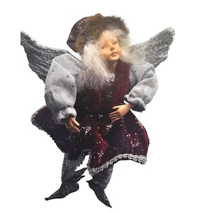 May include: A decorative angel figurine with silver wings, wearing a burgundy sequined dress and a gray sweater. The angel has a fur-trimmed hat and long white hair. The figurine is designed with intricate details.