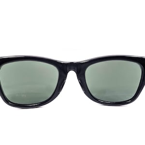 Op de afbeelding: Zwarte zonnebril met een klassiek design. De monturen zijn glanzend zwart en de glazen zijn een gedempt groen. De scharnieren zijn zilverkleurig. Een stijlvol accessoire voor oogbescherming.