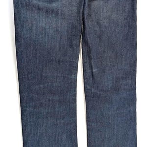 Pode incluir: Jeans de ganga azul escuro com corte reto. Apresentam costuras decorativas douradas nos bolsos traseiros e um remendo de couro na cintura. Os jeans t&ecirc;m um design cl&aacute;ssico de cinco bolsos.