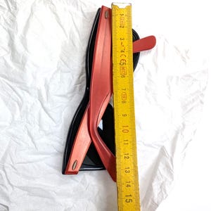 May include: Black and red sunglasses with a ruler showing a measurement of approximately 6 inches. The sunglasses have a classic design with a black frame and red arms. The ruler is yellow with black markings.