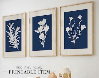May include: Three framed botanical prints with white floral designs on a navy blue background. The prints are in light wood frames and are displayed on a white wall. The text "Blue Yellow Gallery - PRINTABLE ITEM" is at the bottom.