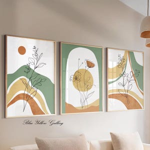 Op de afbeelding: Drie ingelijste abstracte kunstprints met botanische lijntekeningen. Elke print heeft een neutraal kleurenpalet van groen, bruin en geel met een witte achtergrond. De tekst "Blue Yellow Gallery" staat onderaan.