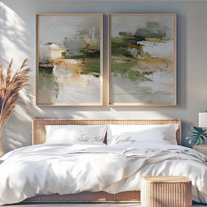 May include: Two framed abstract paintings with neutral tones of green, beige, and white hang above a bed. The bed has white linens and a woven headboard. The text "Blue Yellow Gallery" is on the pillowcases.