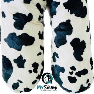 Pode incluir: Um travesseiro de gravidez de vaca branco e preto. O travesseiro tem a forma de U e é projetado para apoiar o corpo durante a gravidez. O travesseiro tem o texto "My Snumi Relax - Sleep - Repeat" na parte inferior.