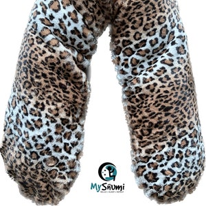 Puede incluir: Una almohada de cuerpo larga en forma de U con estampado de leopardo marrón y blanco. La almohada está hecha de tela suave y de felpa y es perfecta para acurrucarse o dormir.