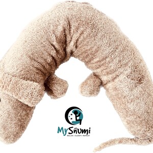 Puede incluir: Una almohada de viaje en forma de U de felpa beige con forma de perro. La almohada tiene una cola larga y una cabeza pequeña y redonda con ojos negros. La almohada está diseñada para brindar soporte al cuello y comodidad durante los viajes. La almohada tiene el texto "My Snumi Relax - Sleep - Repeat" impreso en la parte inferior.