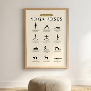 May include: A framed poster with the text "12 Basic Yoga Poses" in a beige and gold color scheme. The poster displays black silhouette illustrations of various yoga poses. The frame is a light wood color.