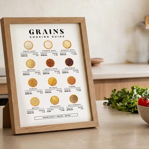 Może przedstawiać: Oprawiony plakat "GRAINS COOKING GUIDE" z jasną drewnianą ramą. Plakat przedstawia r&oacute;żne ziarna z czasami gotowania i proporcjami wody. Miska pomidor&oacute;w i pęczek kolendry stoją na blacie przed plakatem.
