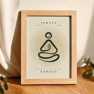 Puede incluir: Una impresión enmarcada con un fondo beige y un dibujo de línea negra de una persona en una postura de yoga. El texto "INHALE" y "EXHALE" está impreso en negro en la parte superior e inferior de la imagen.