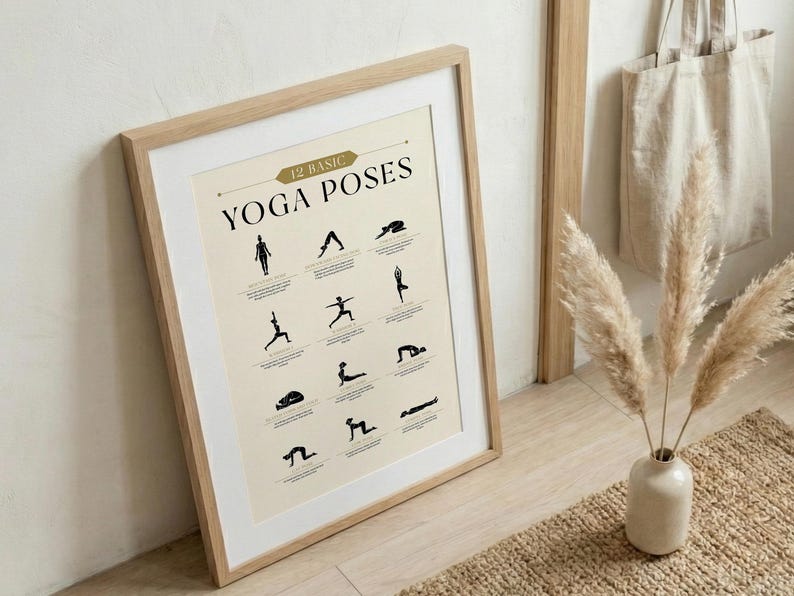 May include: A framed print featuring 12 basic yoga poses in black silhouettes on a cream background. The print is in a light wood frame and leans against a wall. The text "12 Basic Yoga Poses" is at the top.