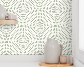 May include: A white wall with a green and white geometric pattern wallpaper. The wallpaper features a repeating pattern of semi-circles with small dots. A white pitcher and a small white jar are sitting on a wooden surface in front of the wall.