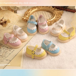 May include: Six pairs of miniature doll shoes in various colors, including pink, blue, and yellow. Each shoe has a white trim and a buckle closure. The shoes are arranged on a light brown surface.