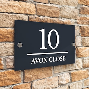 Könnte beinhalten: Schwarzes Hausnummernschild mit weißer Beschriftung. Die Nummer 10 und die Worte "Avon Close" sind auf dem Schild zu sehen.