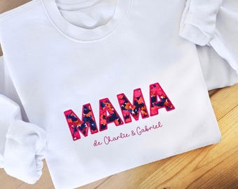 May include: White sweatshirt with the word "MAMA" in pink outlined letters with a floral pattern inside. The text "de Charlie & Gabriel" is written below in pink.