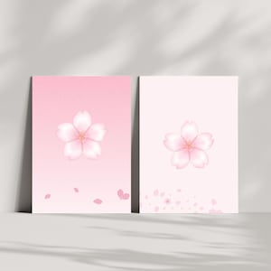 Puede incluir: Dos impresiones artísticas florales rosas. Cada impresión presenta una delicada flor de cerezo al estilo acuarela. El fondo de una impresión es un degradado de rosa, la otra es rosa claro liso. Pétalos dispersos añaden detalles.