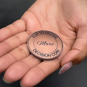 May include: A copper-colored coin with the text "Flip to Decide" and "Decision Coin" around the edge. The name "Marc" is inscribed in the center.