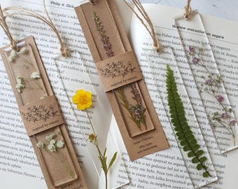 May include: Three clear bookmarks with pressed flowers and greenery inside. The bookmarks are on a brown surface with text that reads "inspired by nature".