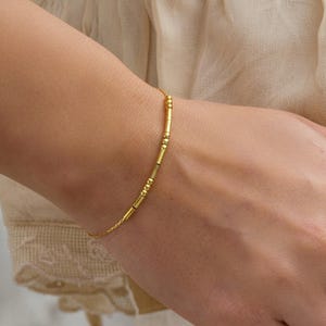 Könnte beinhalten: Eine weiße Keramik-Tasse mit schwarzem Henkel und dem Text "But First, Coffee" in fetter, schwarzer Schrift. Die Tasse steht vor einem verschwommenen Hintergrund, der eine gemütliche Umgebung suggeriert.