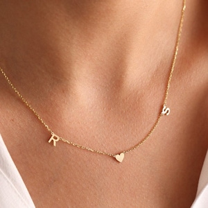 May include: A gold chain necklace with a heart charm and two initial charms, one 'R' and one 'S'.