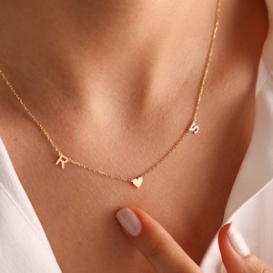 Puede incluir: Un collar de oro con un dije de coraz&oacute;n y dos dijes con iniciales. Las iniciales son "R" y "S".