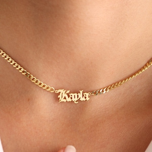 May include: Gold chain necklace with a gold pendant that says "Kayla" in a gothic font.