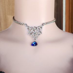 May include: Silver choker necklace with a Celtic knot pendant and a blue gemstone drop.