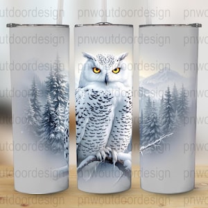 May include: A set of three white insulated tumblers. Each tumbler features a winter scene with a snowy owl perched on a branch, set against a backdrop of snow-covered trees and mountains. The tumblers are cylindrical and have a silver lid.