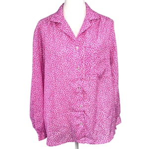May include: A long-sleeved button-down shirt in a vibrant pink hue, adorned with a delicate floral pattern. The shirt features a classic collar and button closure, offering a timeless style. The fabric appears soft and lightweight, suitable for various occasions.