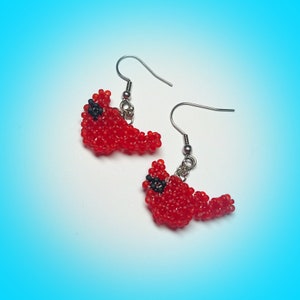 May include: A pair of red cardinal earrings made of beads with silver hooks.