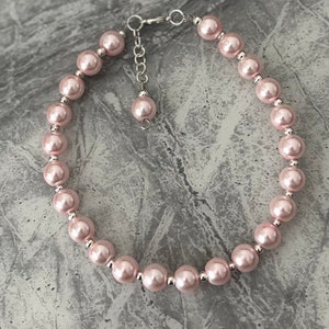 Puede incluir: Un collar de perlas rosas con un cierre plateado y una cadena de extensión.