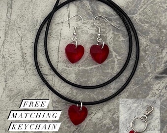 Könnte beinhalten: Eine schwarze Choker-Kette mit einem roten Herz-Anhänger, dazu passende rote Herz-Ohrringe und ein roter Herz-Schlüsselanhänger. Der Text "FREE GIFT WRAP" und "FREE MATCHING KEYCHAIN" ist ebenfalls im Bild enthalten.