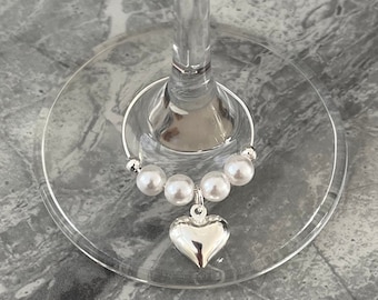 May include: Silver wine glass charm with a heart pendant and a string of white pearls.